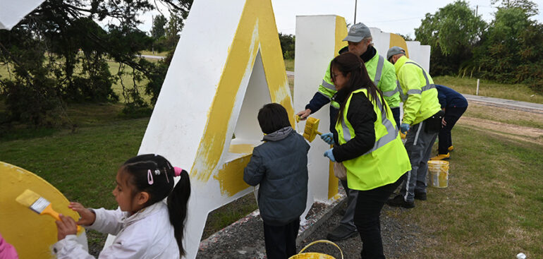 Niños pintando las letras de amarillo