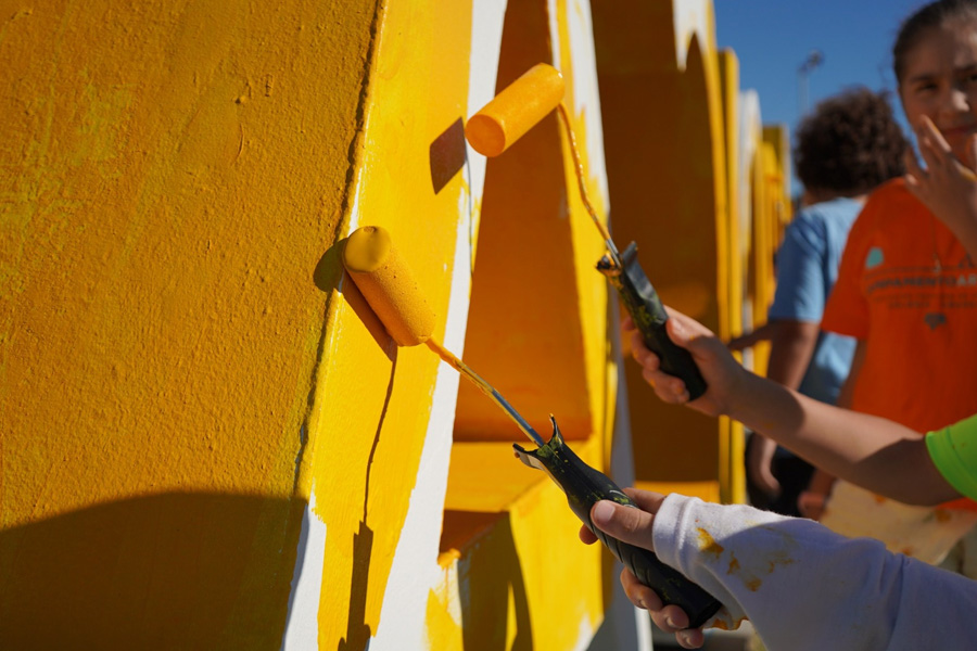 Niños pintando letras de amarillo